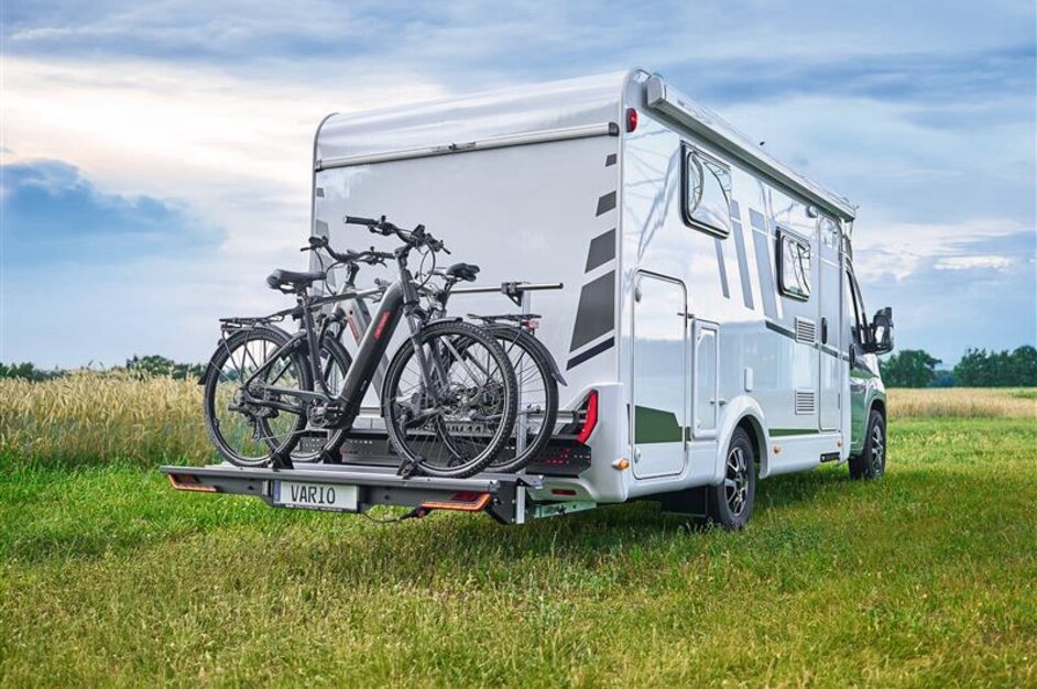 Weißes Wohnmobil auf einer Wiese mit SAWIKO VARIO Fahrradträger auf dem zwei Fahrräder montiert sind. | © AL-KO VT
